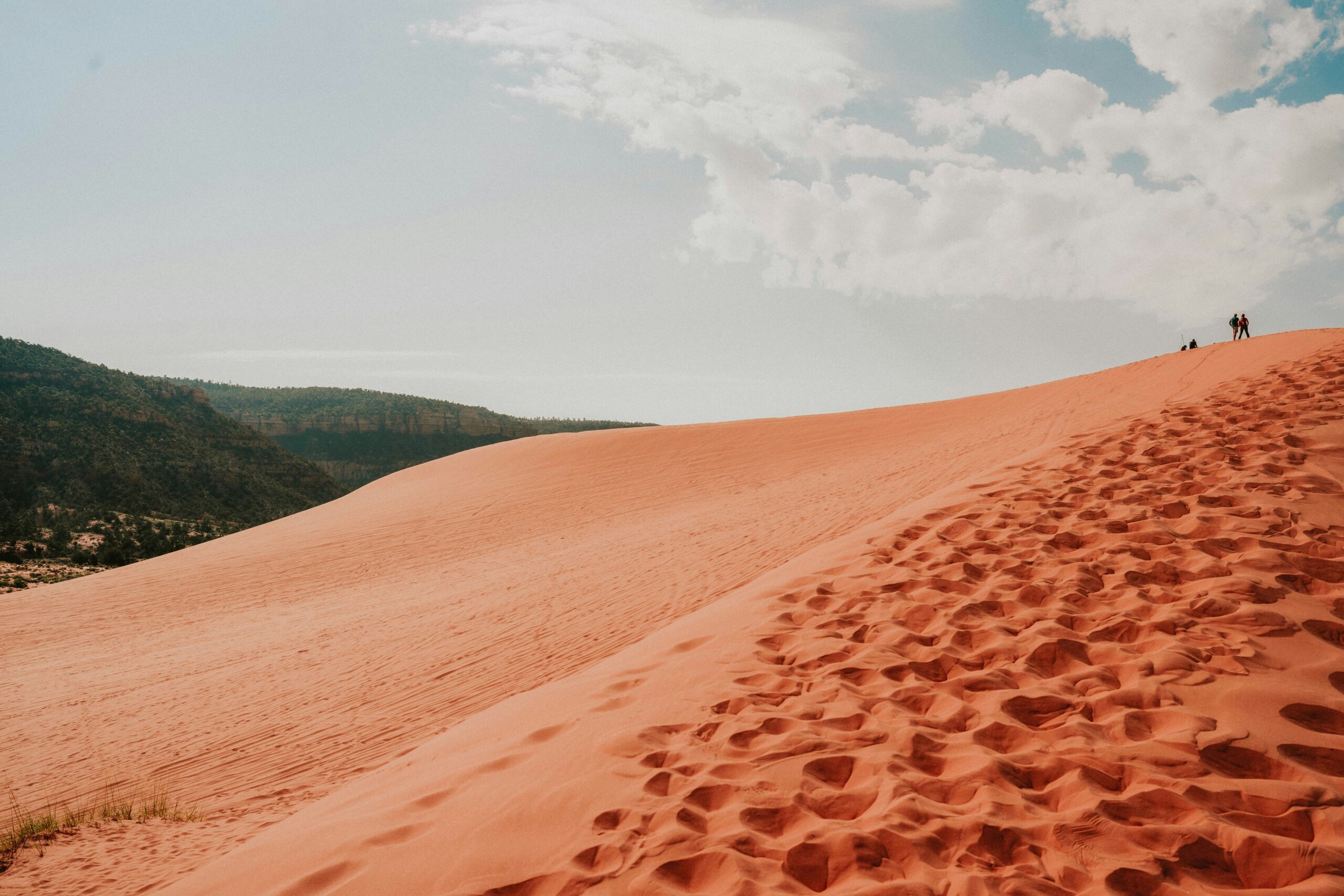 Hikers walking up a dune at Coral Pink Sand Dunes State Park, a short drive from downtown Kanab