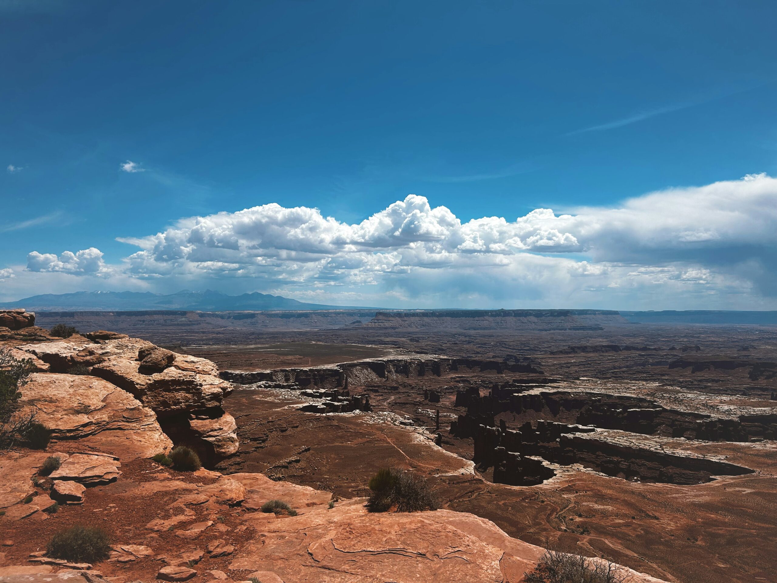 Vast red-rock landscape at Canyonlands Island in the Sky district with a deep canyon and layered mesas stretching to the horizon