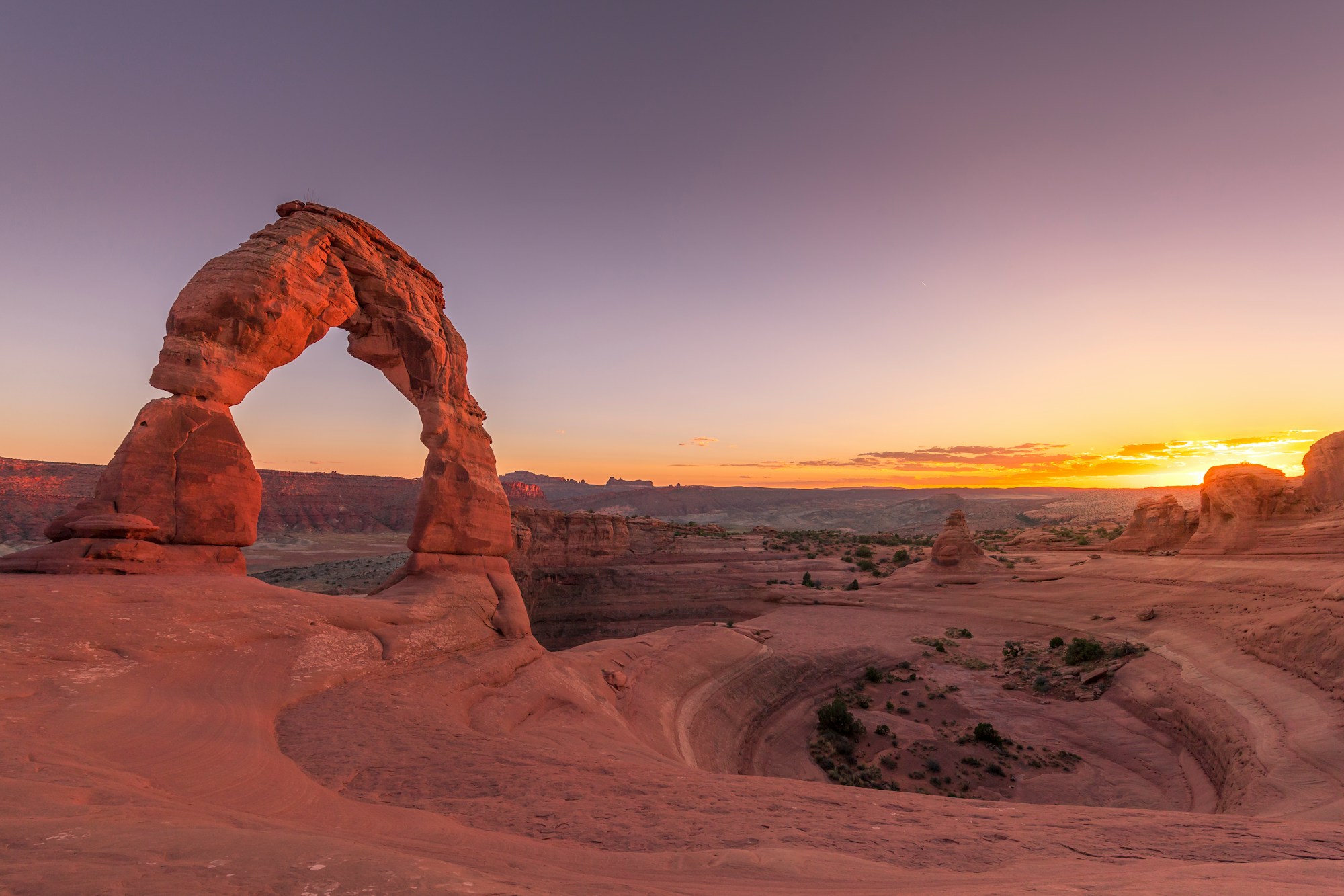 Delicate Arch glowing orange at sunset in Arches National Park, Utah